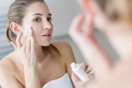 Woman applying cream on her face in a bathroom